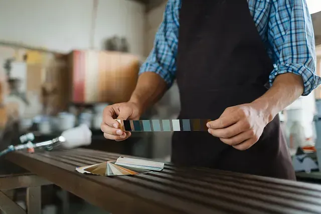 Un hombre con delantal sostiene una paleta de colores en sus manos.