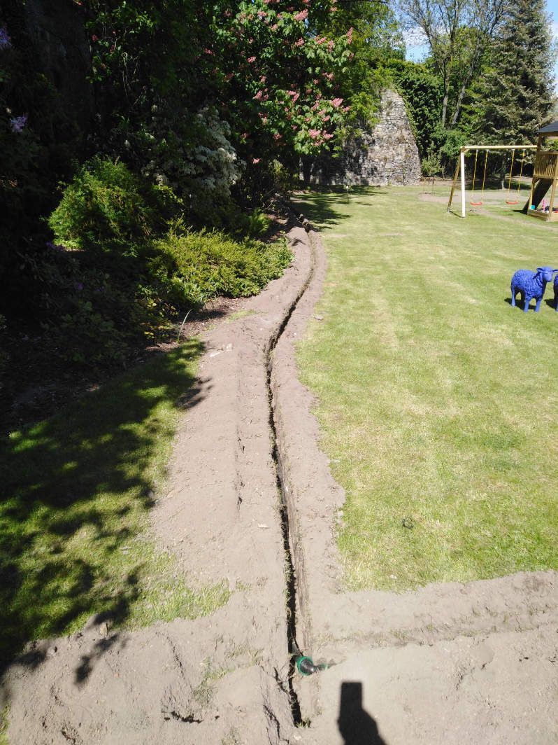 Eine Rinne im Rasen zur Verlegung der Bewässerungsanlage