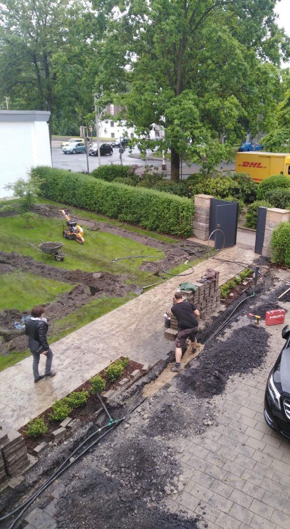 Installation einer Bewässerungsanlage im Garten mit einem Gehweg vor einem Haus.