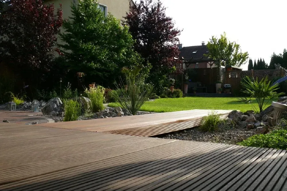Eine Holzterrasse in einem Garten mit Bäumen im Hintergrund