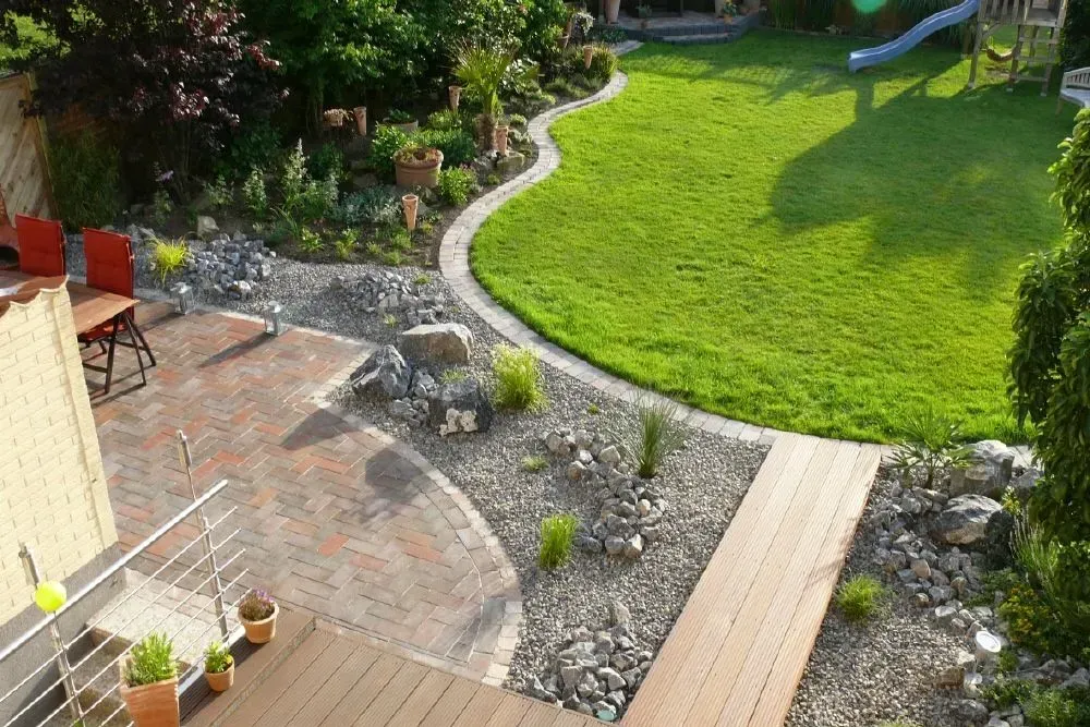 Eine Luftaufnahme eines üppig grünen Rasens mit einer Steinterrasse und Holzwegen