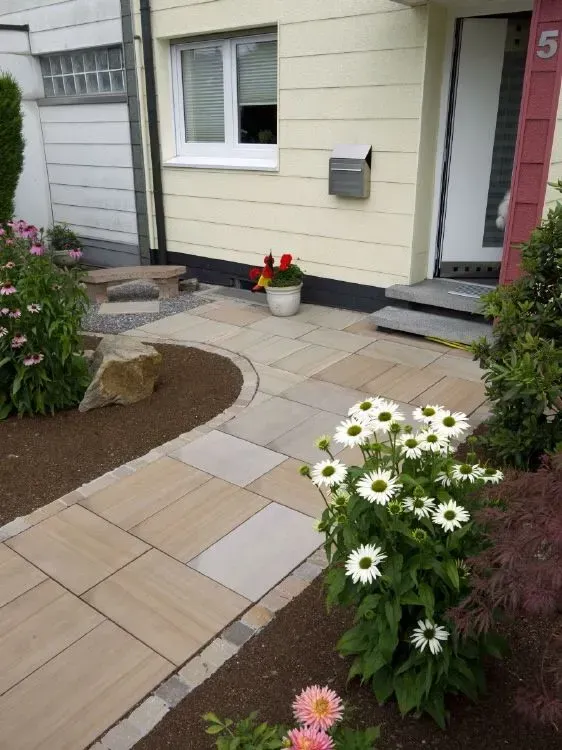 Ein Haus mit gepflastertem Weg und Blumen an den Seiten