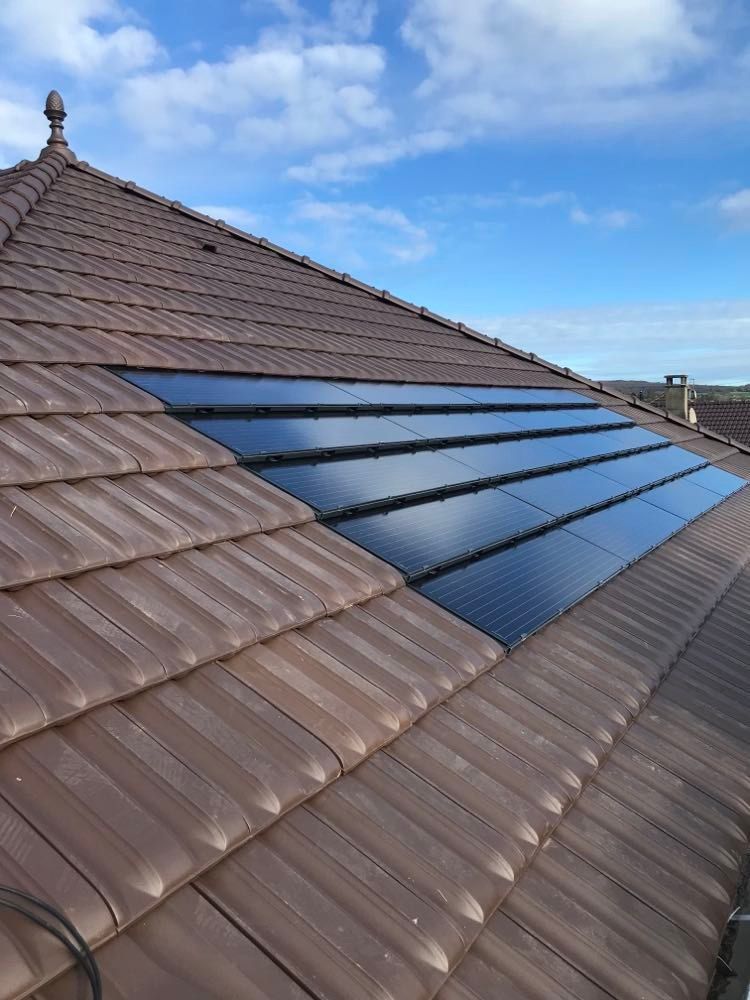 Des panneaux solaires installés sur un toit de tuiles brunes sous un ciel bleu