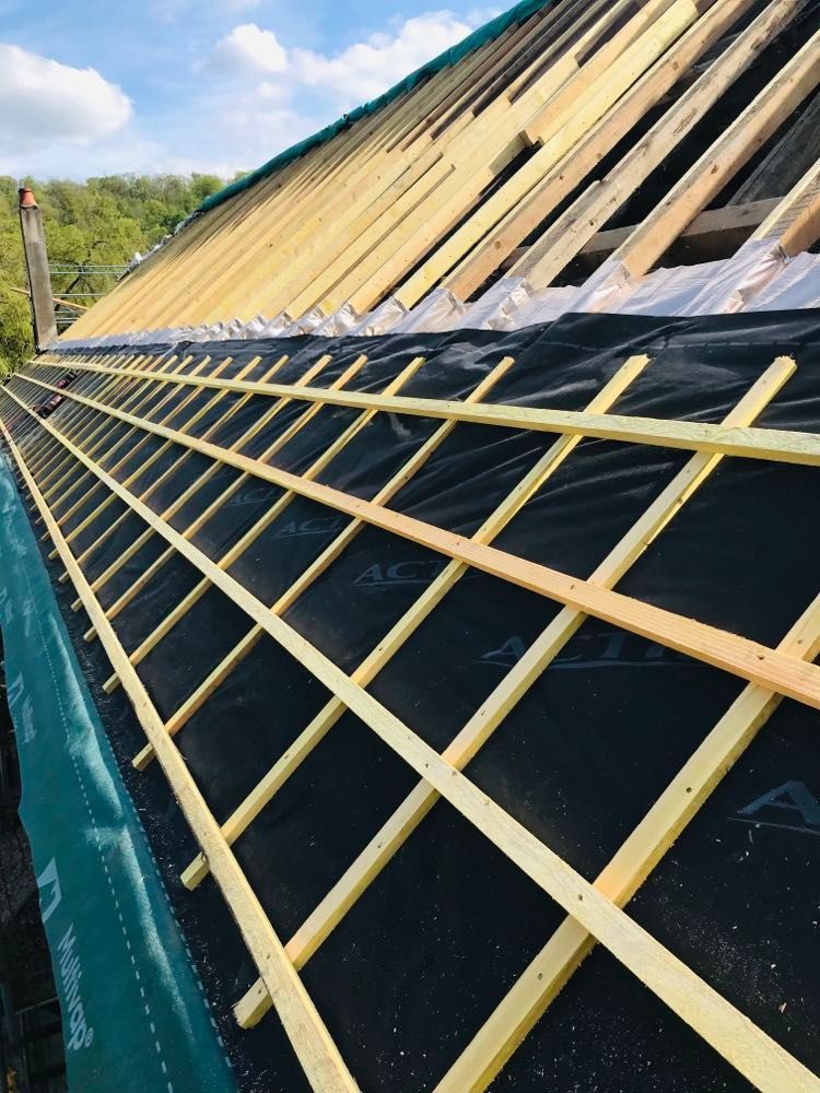 Toiture en construction avec liteaux jaunes sur feutre bitumé noir sur une charpente inclinée