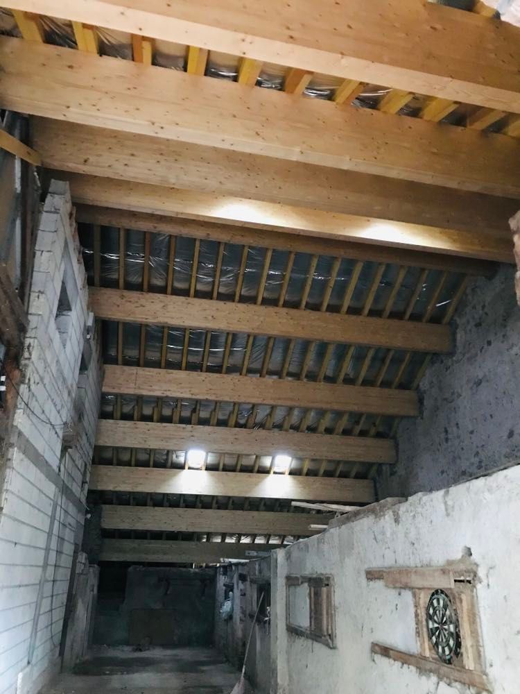 Intérieur d'un chantier de construction avec poutres de plafond en bois apparentes et murs en briques non finies