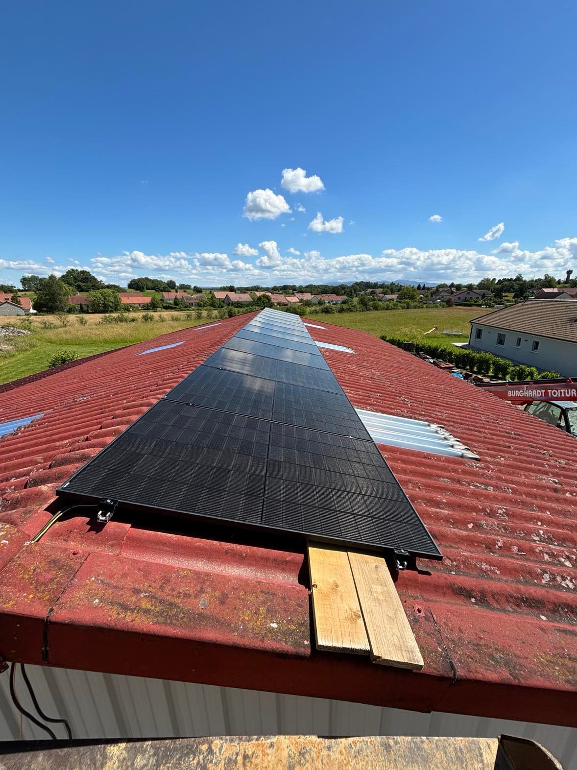 Panneau solaire installé sur un toit rouge sous un ciel d'un bleu éclatant