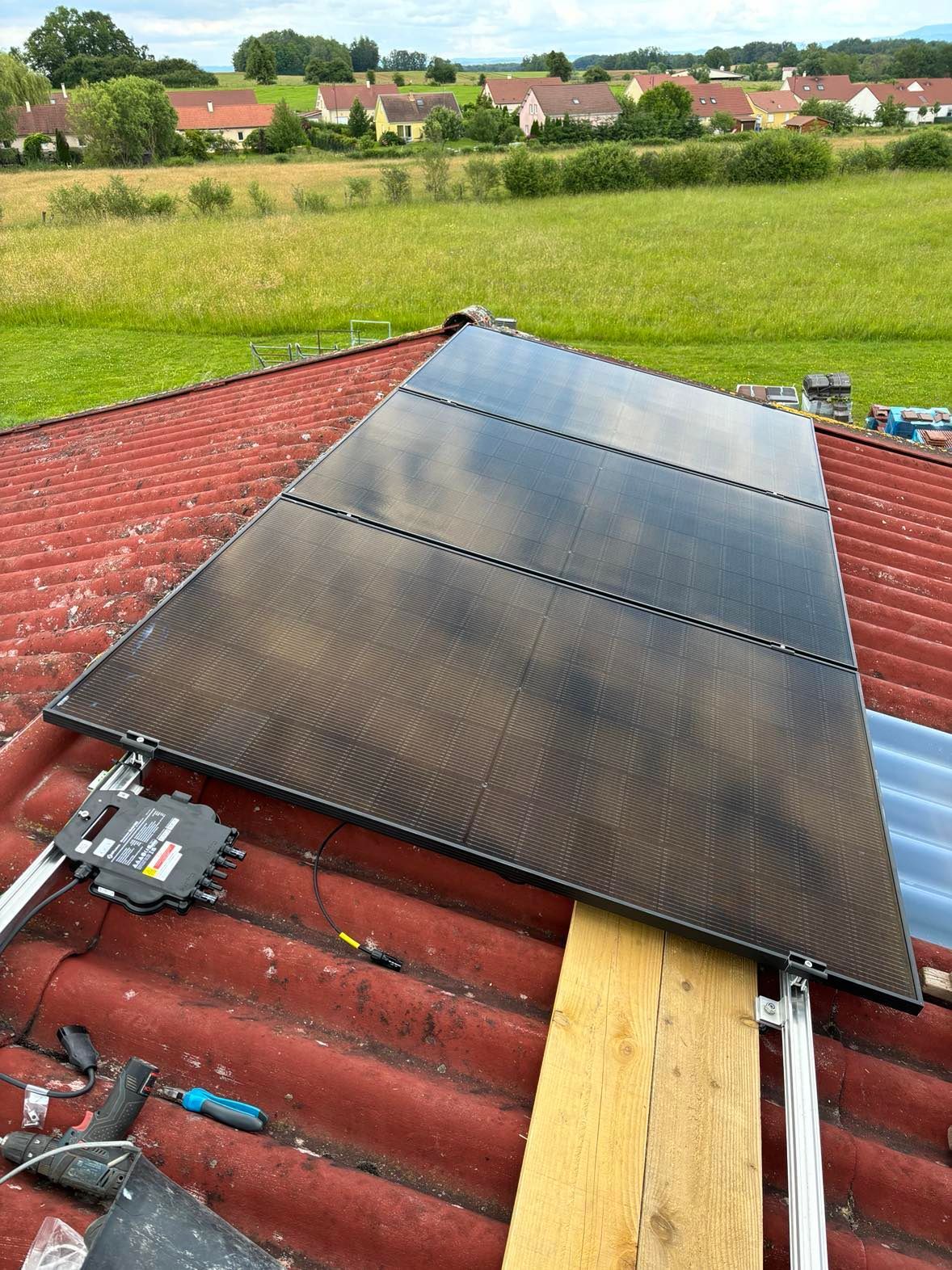 Panneaux solaires installés sur un toit rouge dans un paysage rural