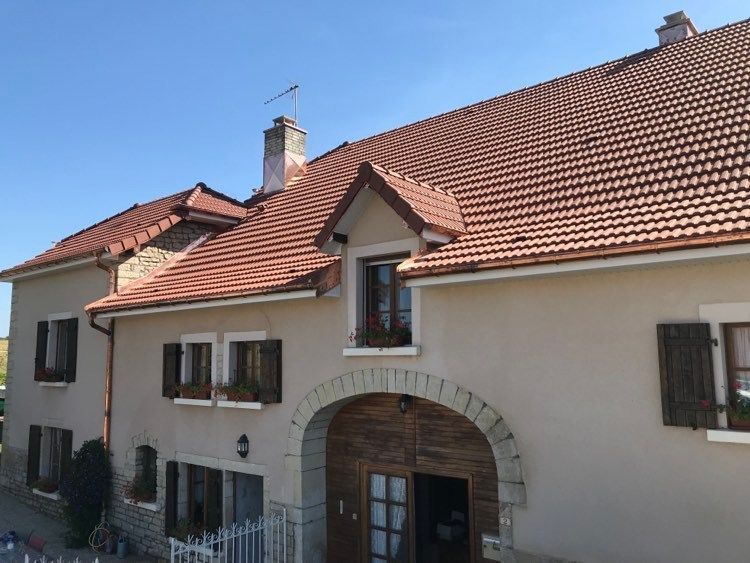 Maison blanche au toit de tuiles rouges et à la porte cintrée sous un ciel bleu