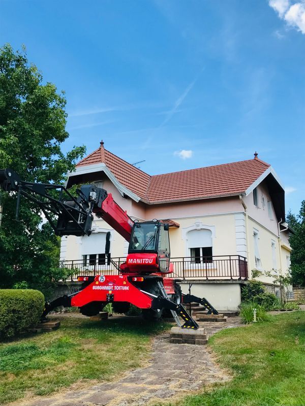 Une maison blanche au toit de tuiles rouges, sous un ciel bleu.