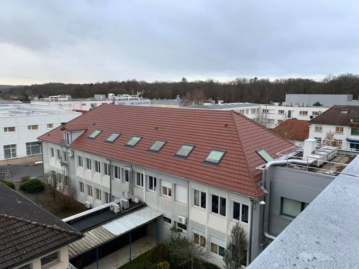 Vue aérienne de bâtiments blancs au toit de tuiles rouges dans un quartier résidentiel sous un ciel nuageux