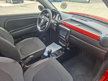 Intérieur de voiture avec sièges noirs, garniture de tableau de bord rouge et vue du volant côté passager avant.