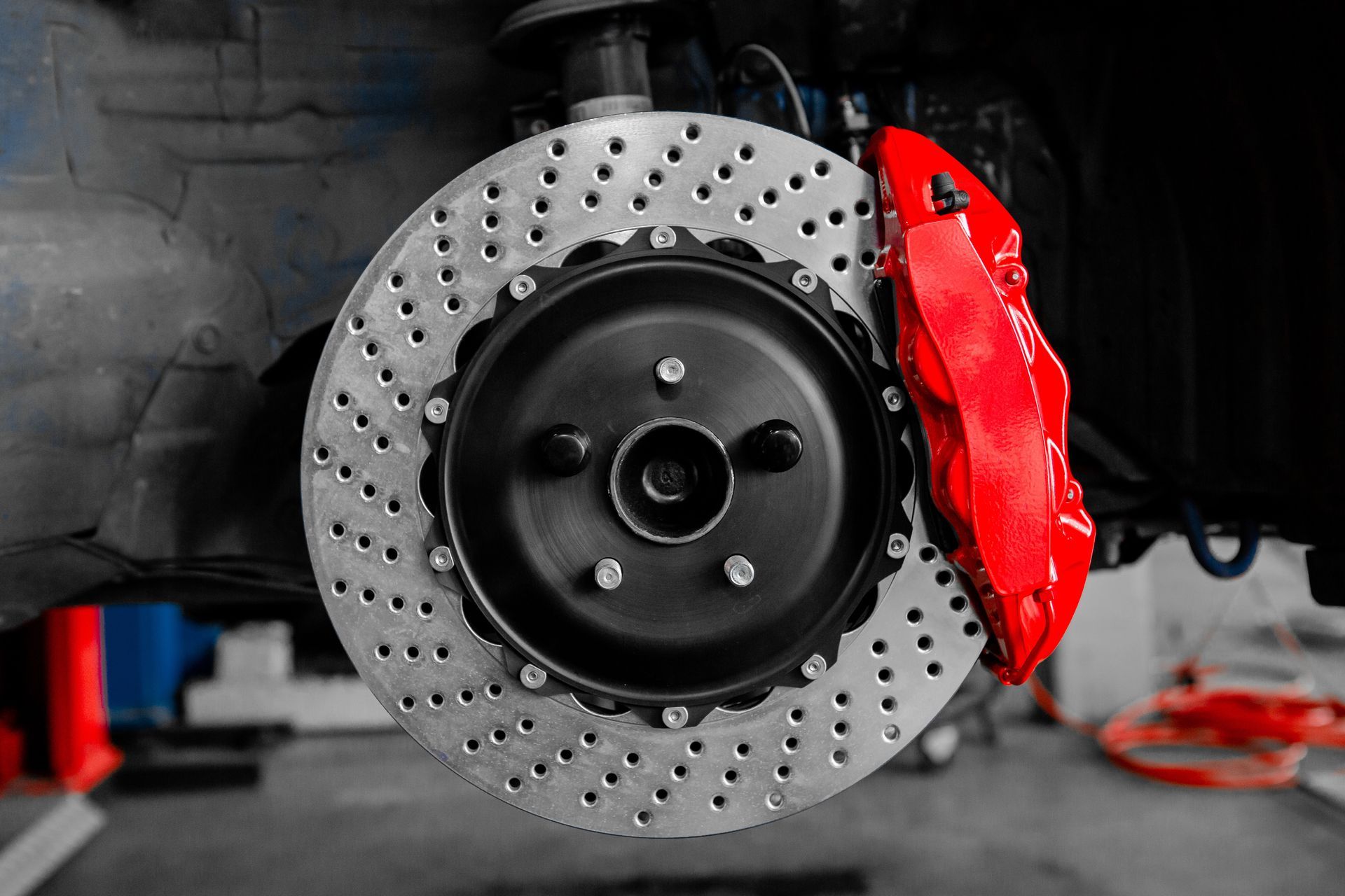 Roue de voiture avec disque de frein percé et étrier de frein rouge vif dans un garage