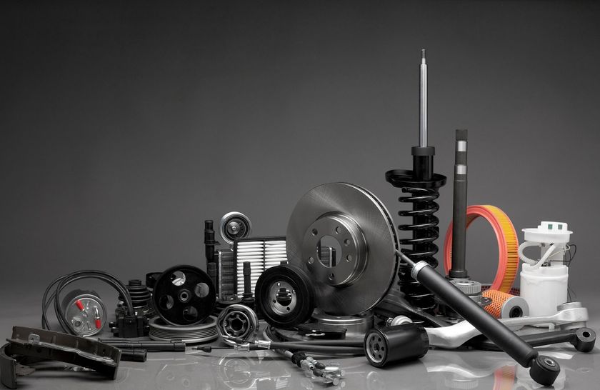 Pièces automobiles et outils divers disposés sur une surface réfléchissante, notamment des engrenages, des courroies et des composants de freins.