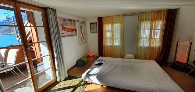 Ein Massageraum mit Massagetisch, Kunstwerken und einem gedeckten Tisch für eine Mahlzeit.