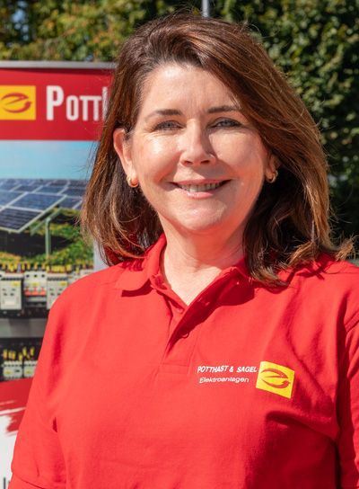 Frau in rotem Poloshirt lächelt; im Hintergrund Banner mit Logo und Solarpaneelen.