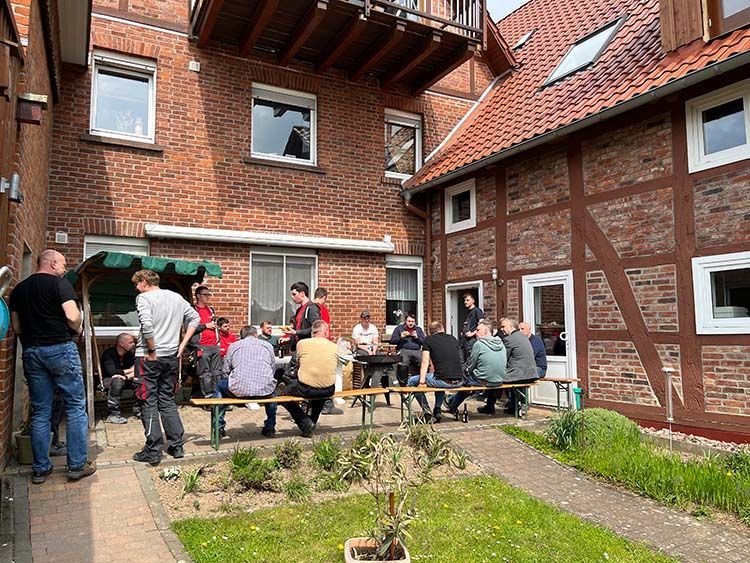 Die Menschen versammelten sich im Freien und saßen an Picknicktischen in der Nähe von Backsteingebäuden.