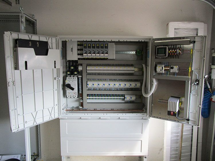 Offener Schaltschrank mit verschiedenen Sicherungsautomaten, Schaltern und einem Kontrollbildschirm.