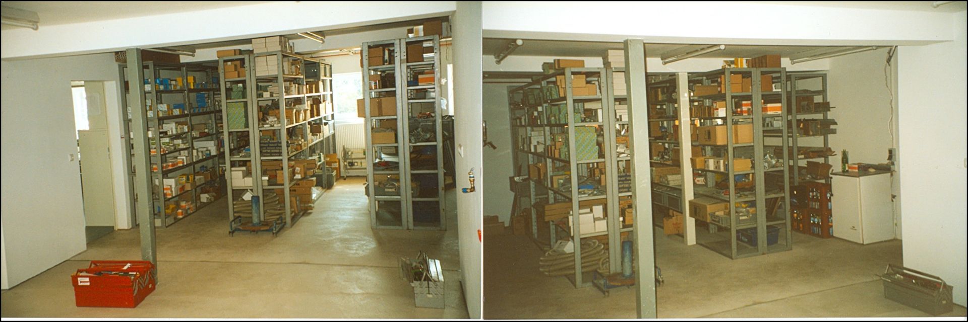 Ein vollgestellter Raum mit Metallregalen, die mit Kisten gefüllt sind. Ein roter Werkzeugkasten auf dem Boden