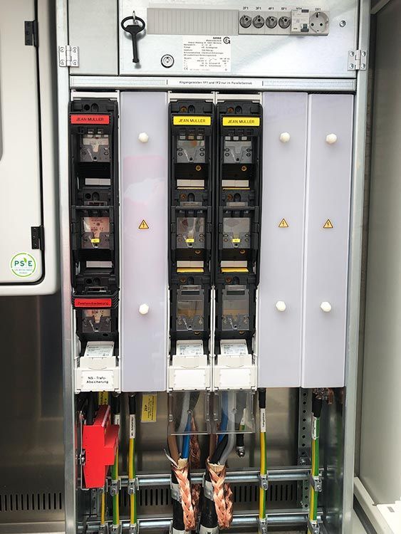 Schaltschrank mit Sicherungen, Verkabelung und Sicherheitshinweisen.