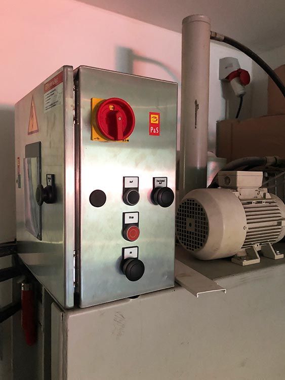 Bedienfeld aus Edelstahl mit rotem Schalter, Knöpfen und Motor.