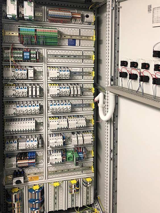 Elektrischer Schaltschrank mit Reihen von Leistungsschaltern, Drähten und anderen Bauteilen, montiert auf einem Metallrahmen.