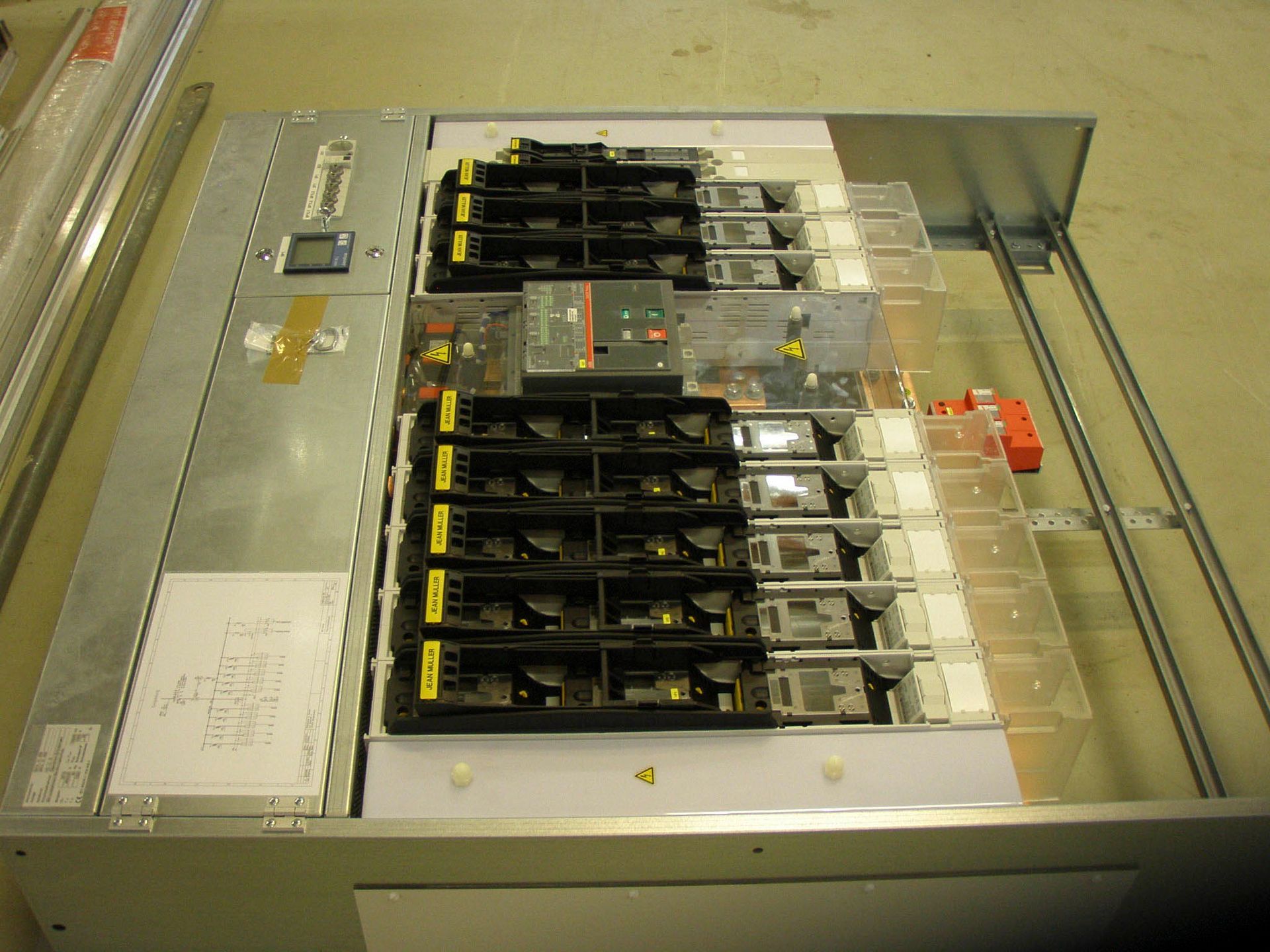 Schaltschrank mit Sicherungsautomaten, Kabeln und Sicherheitshinweisen. Metallgrau.