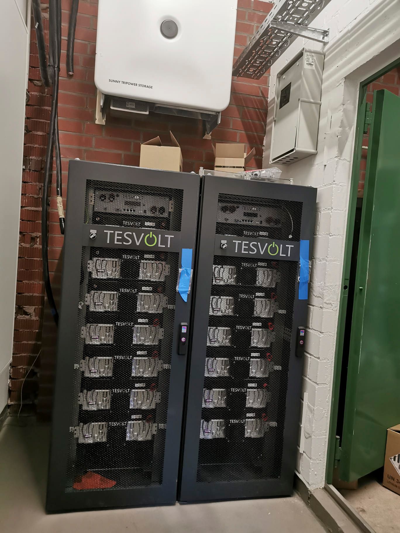 Zwei TESVOLT-Batteriegestelle und ein Solarwechselrichter in einem Hauswirtschaftsraum.