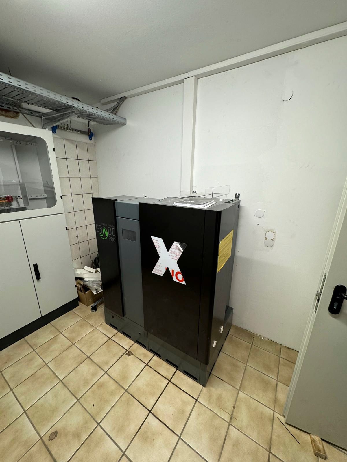 CNC-Maschine in einem kleinen Raum. Schwarzes und graues Gehäuse, weiße Wände,