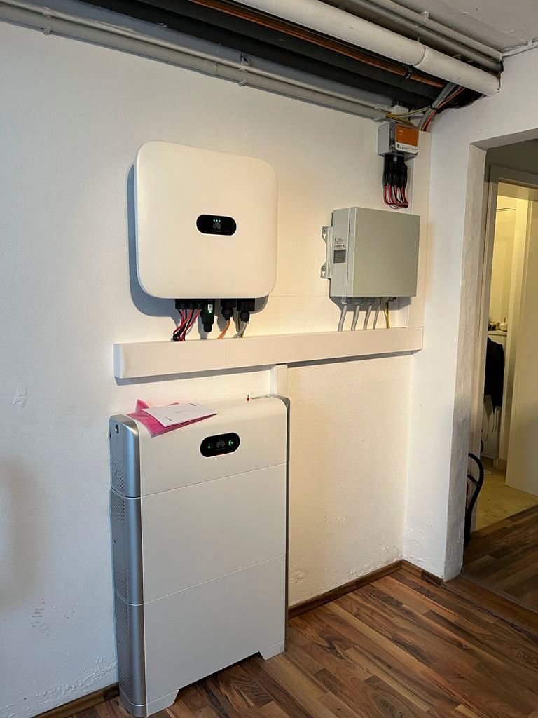 Solarmodulanlage an einer weißen Wand in einem Raum mit Holzboden.