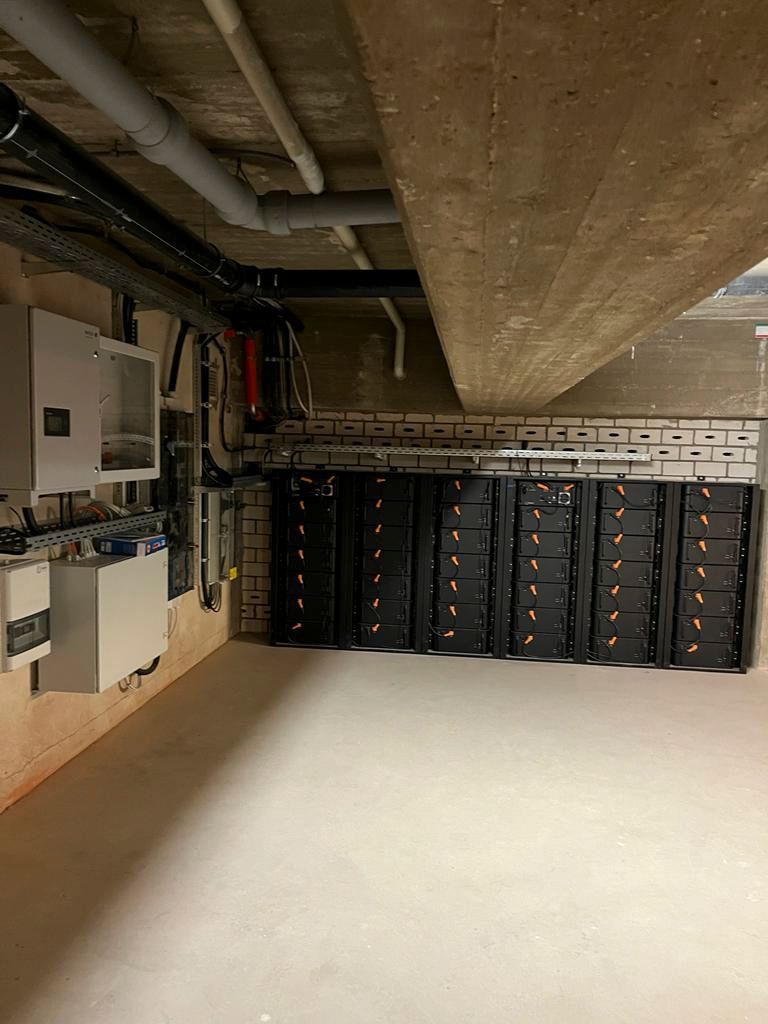 Batteriespeichersystem in einem Hauswirtschaftsraum mit elektrischen Schalttafeln und Leitungen an den Wänden.