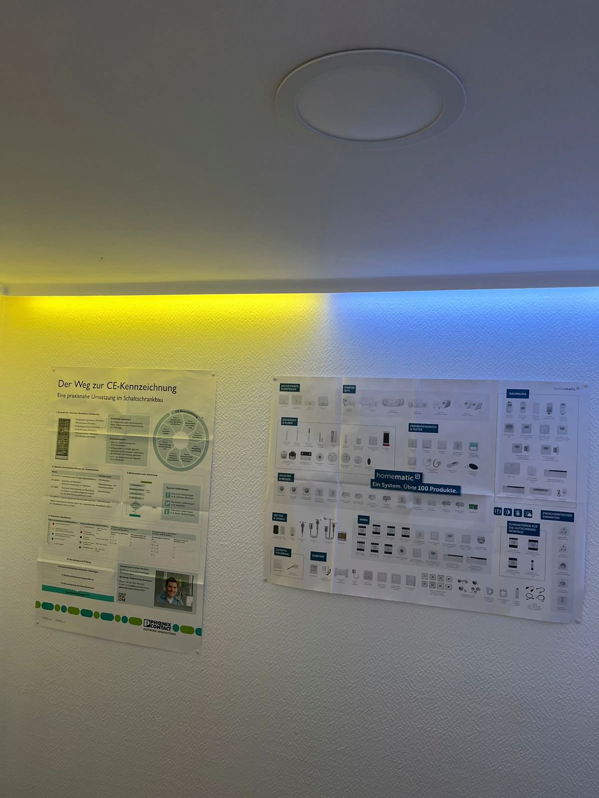 Zwei Diagramme hängen an einer weißen Wand, die mit gelbem und blauem Licht beleuchtet ist. 
