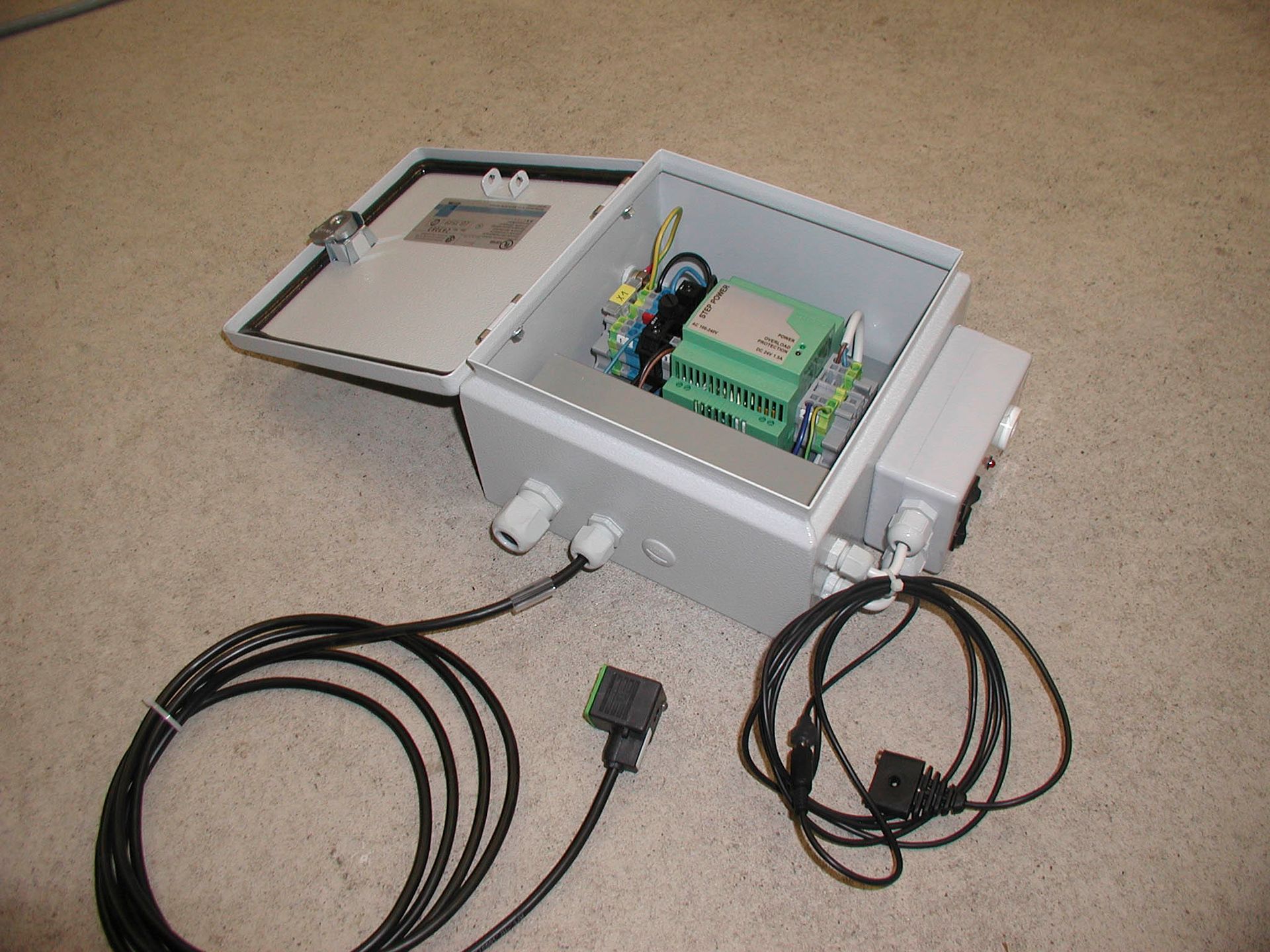 Offener grauer Elektroschrank mit Drähten, Kabeln und elektronischen Bauteilen.