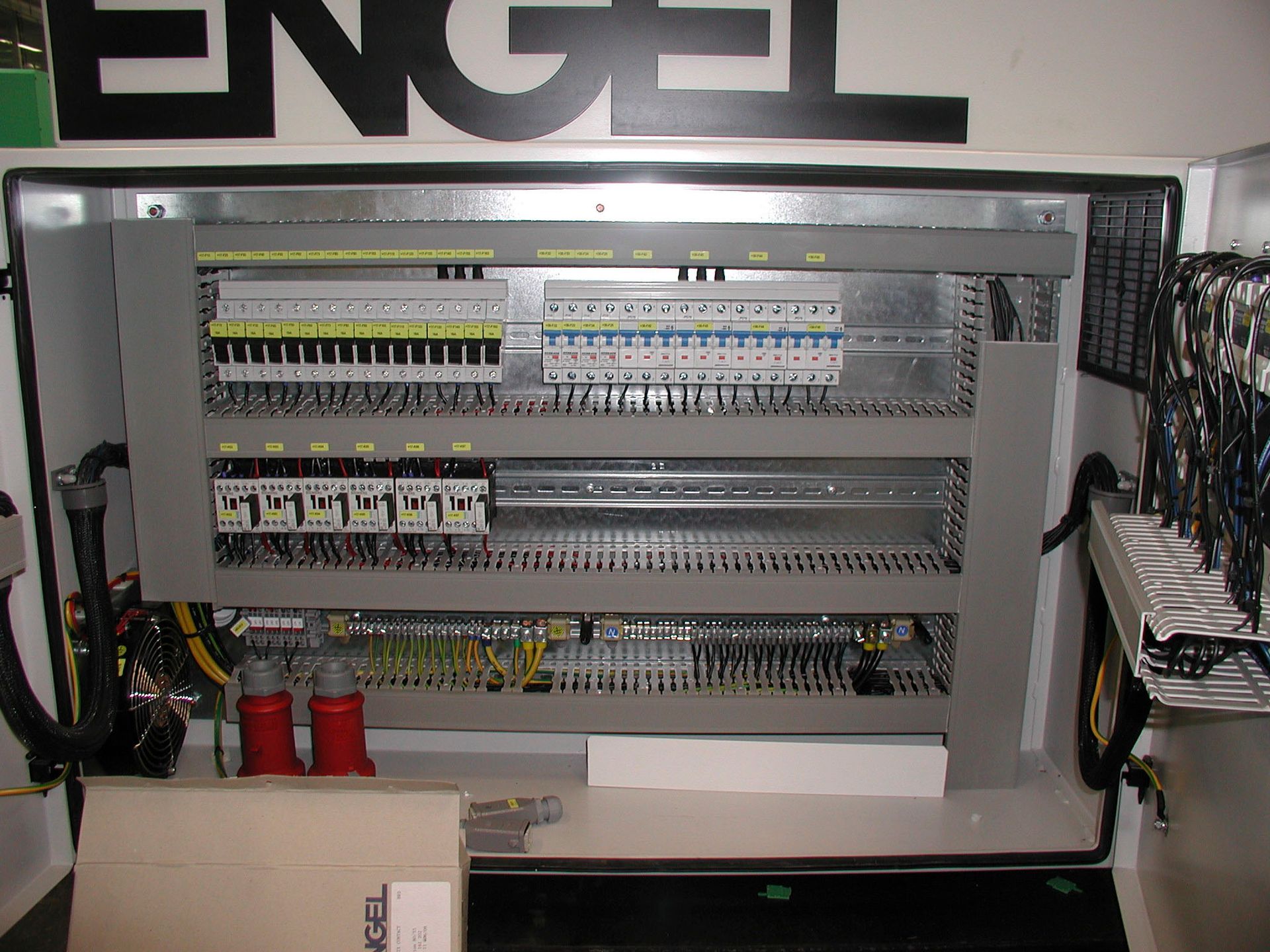 Elektrischer Schaltschrank mit Reihen von Leistungsschaltern, Drähten und Steckverbindern, montiert in einem Gehäuse.