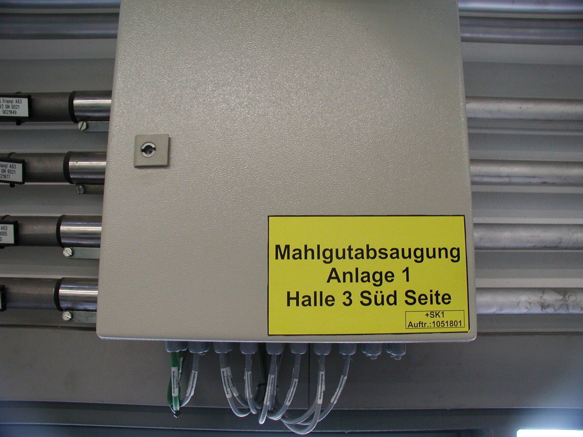 Grey metal control box with yellow sign reading 