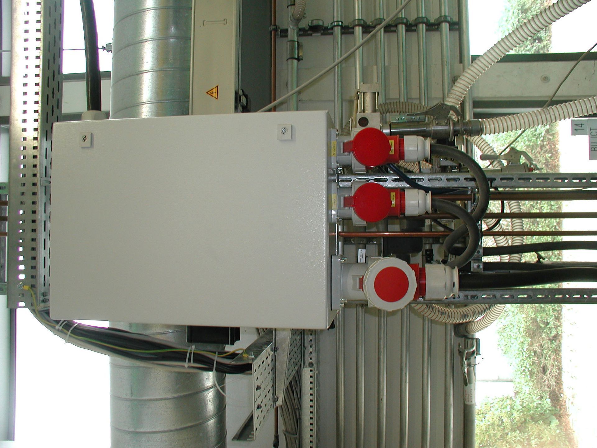 Weißer Elektroverteilerkasten mit roten und weißen Stromanschlüssen, montiert auf einer Metallkonstruktion.