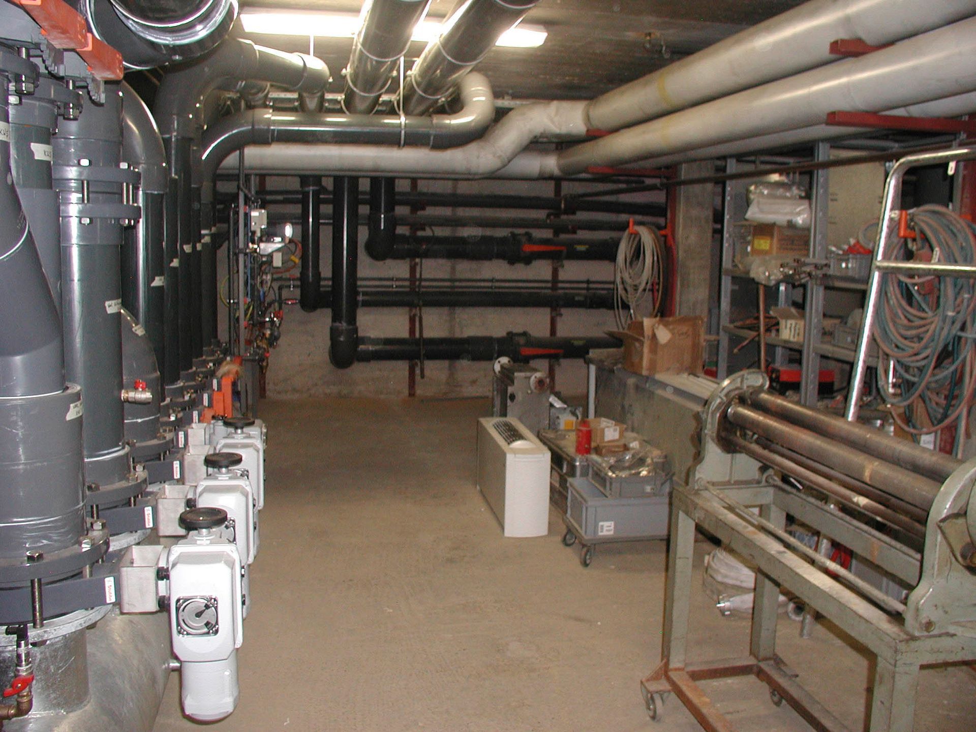 Kellerraum mit Rohren, Maschinen und Werkzeugen; möglicherweise ein Maschinenraum.