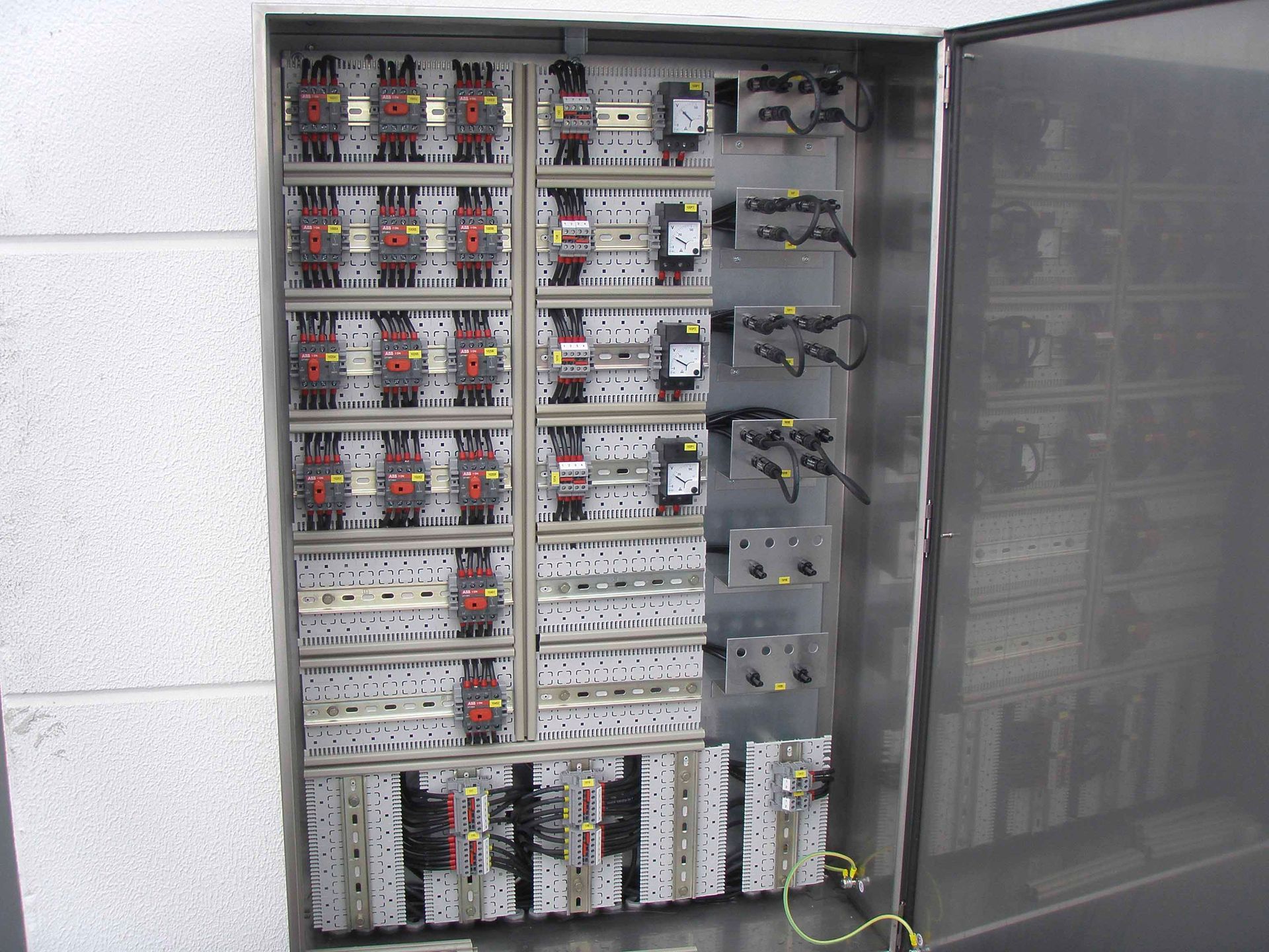 Offener Schaltschrank mit zahlreichen Sicherungsautomaten und Verkabelung.