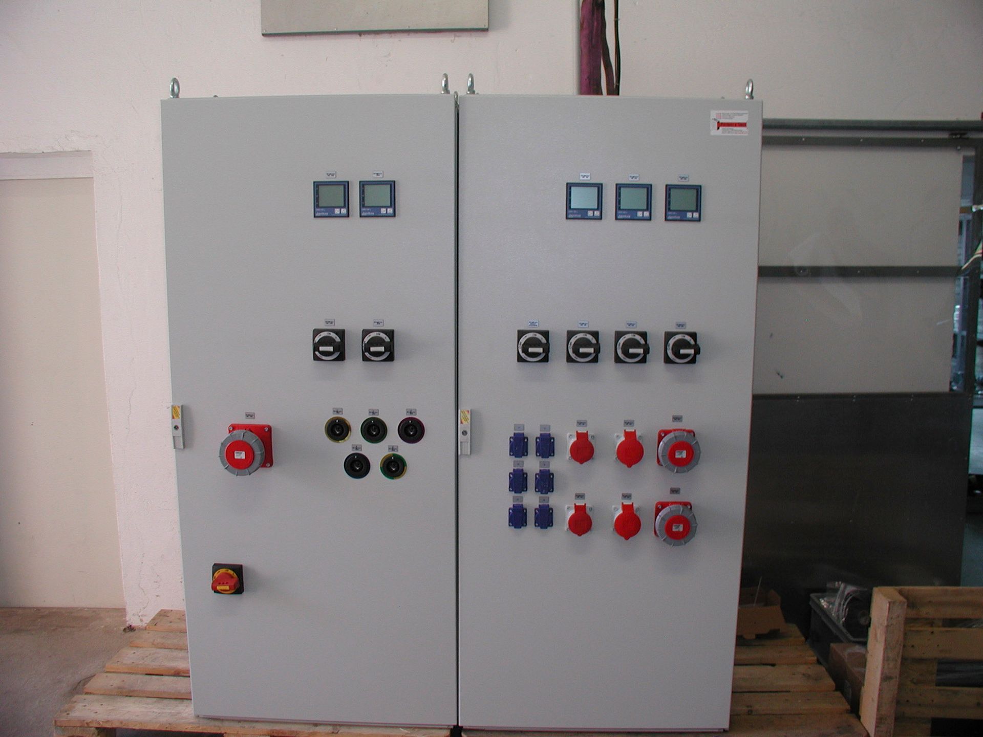 Zwei graue elektrische Schalttafeln mit Anzeigen, Schaltern und Steckdosen.