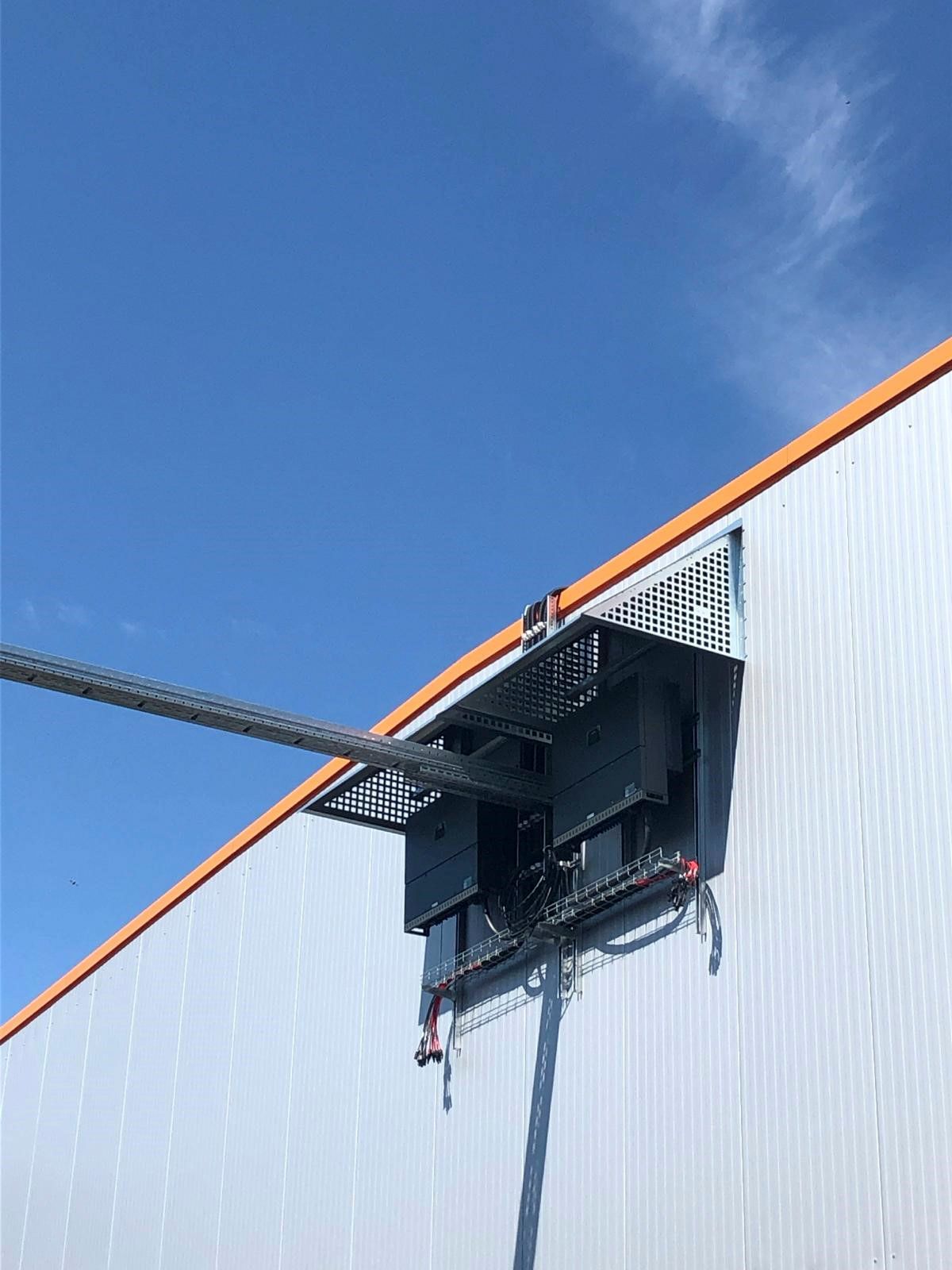 Großer elektrischer Verteilerkasten an der Außenfassade eines weißen Industriegebäudes