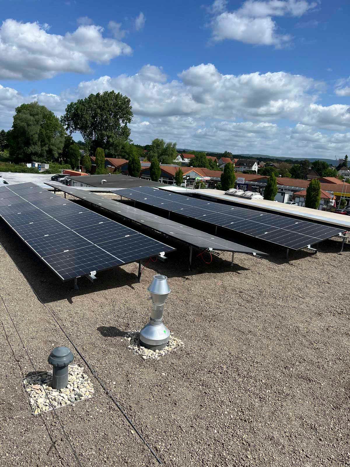 Solarpaneele auf einem Flachdach mit Stadtgebäuden im Hintergrund unter blauem Himmel.
