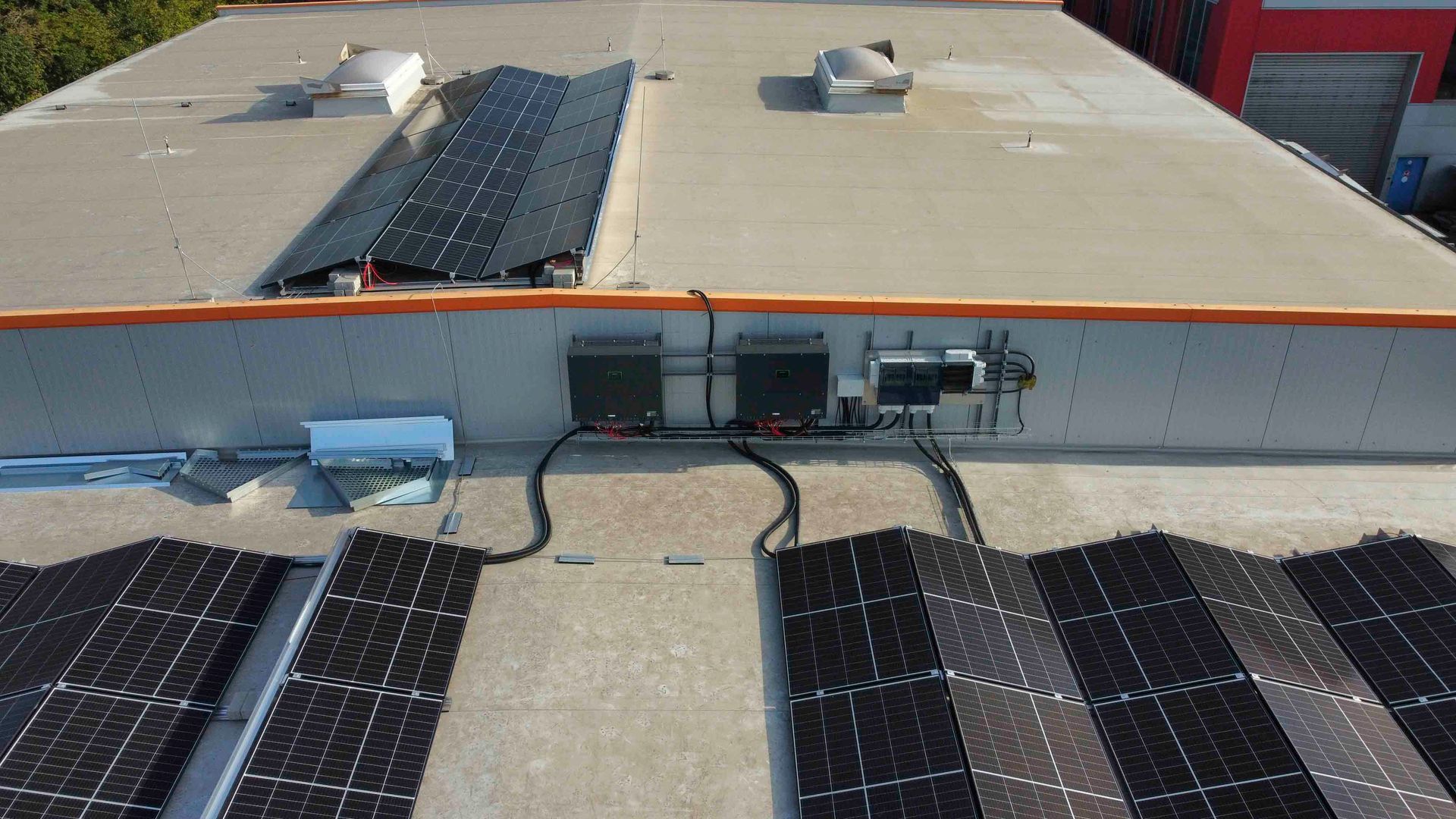Solarpaneele auf einem Gebäudedach, Wechselrichter und Verkabelung sind sichtbar.
