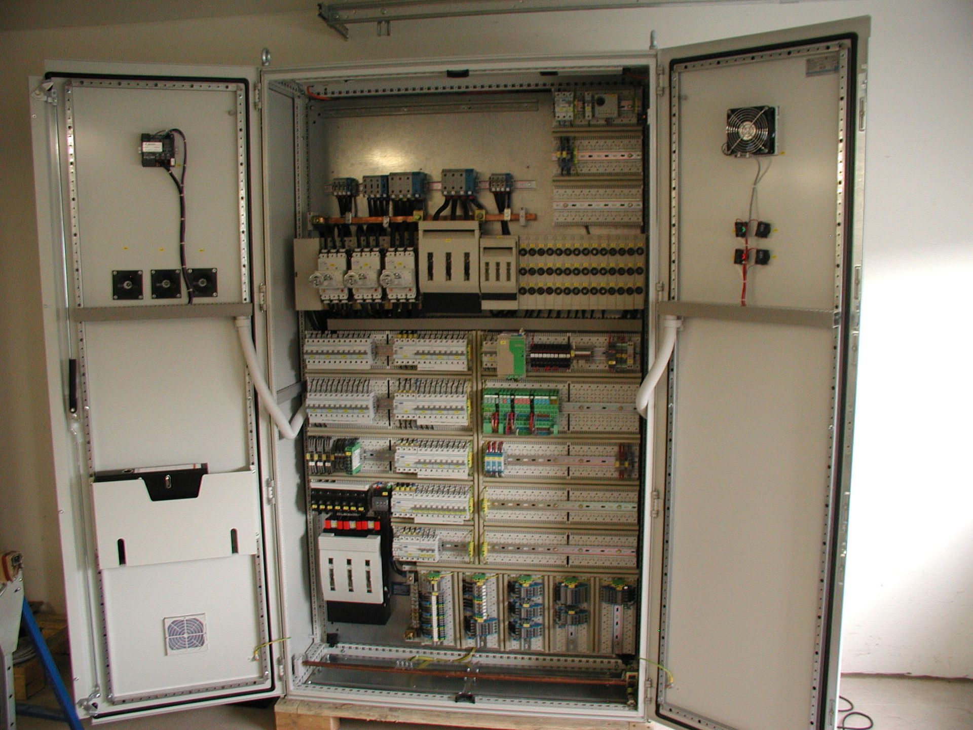 Offener elektrischer Schaltschrank mit verschiedenen Bauteilen und Verkabelung.