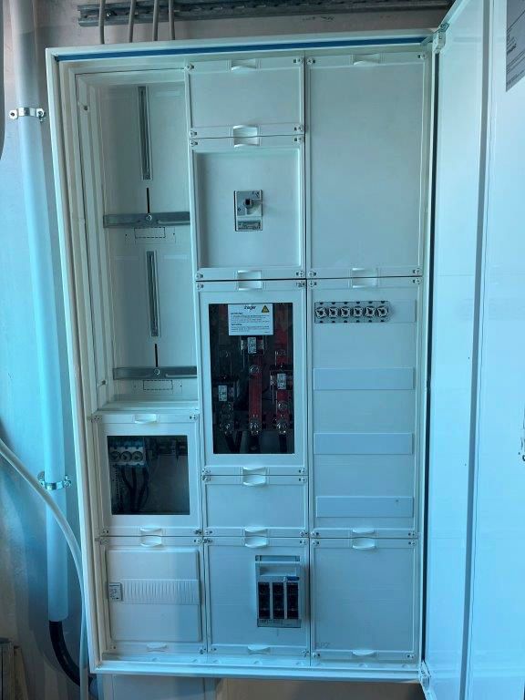 Weißer Schaltschrank mit mehreren Fächern und verschiedenen Komponenten.