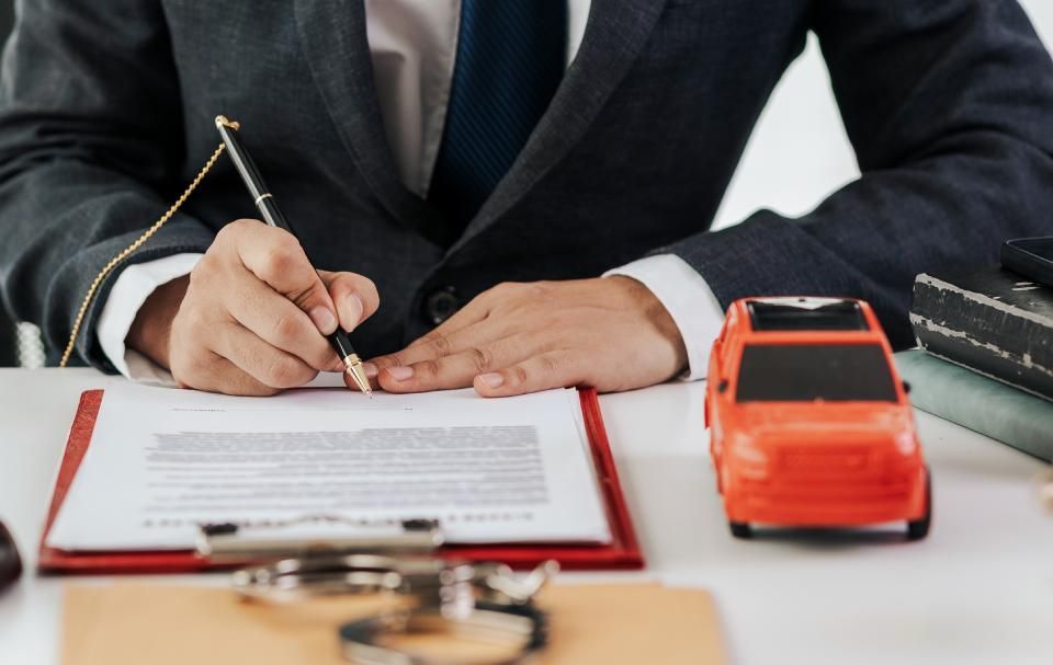 Rechtsanwalt Bernd Scheske - Mann im Anzug sitzt vor Modellauto und Handschellen