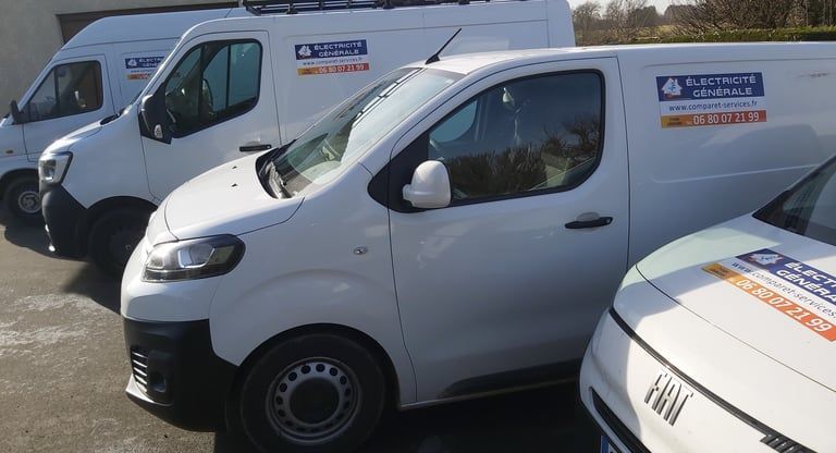 Deux fourgonnettes de travail blanches garées côte à côte sur un parking extérieur, le véhicule de devant montrant son profil latéral.