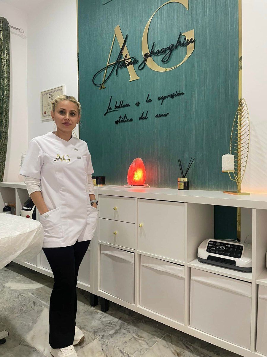 Dueña del negocio delante de la pared con el logotipo