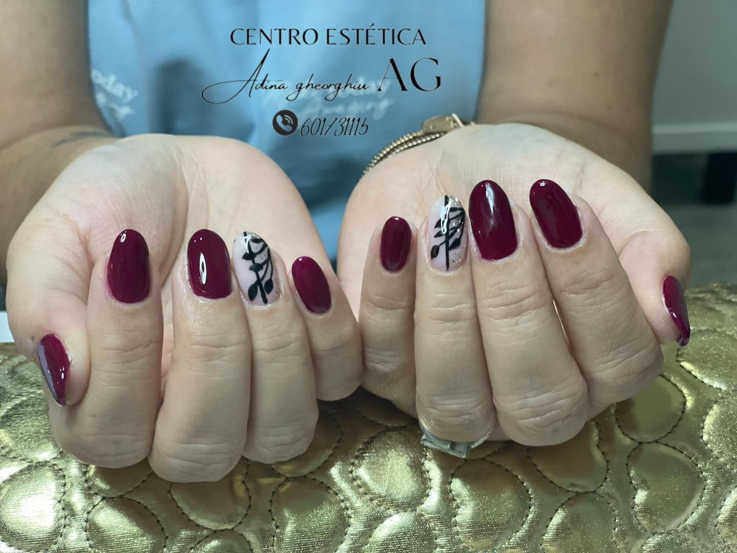 Manos con nail art floral en tonos burdeos y negro.