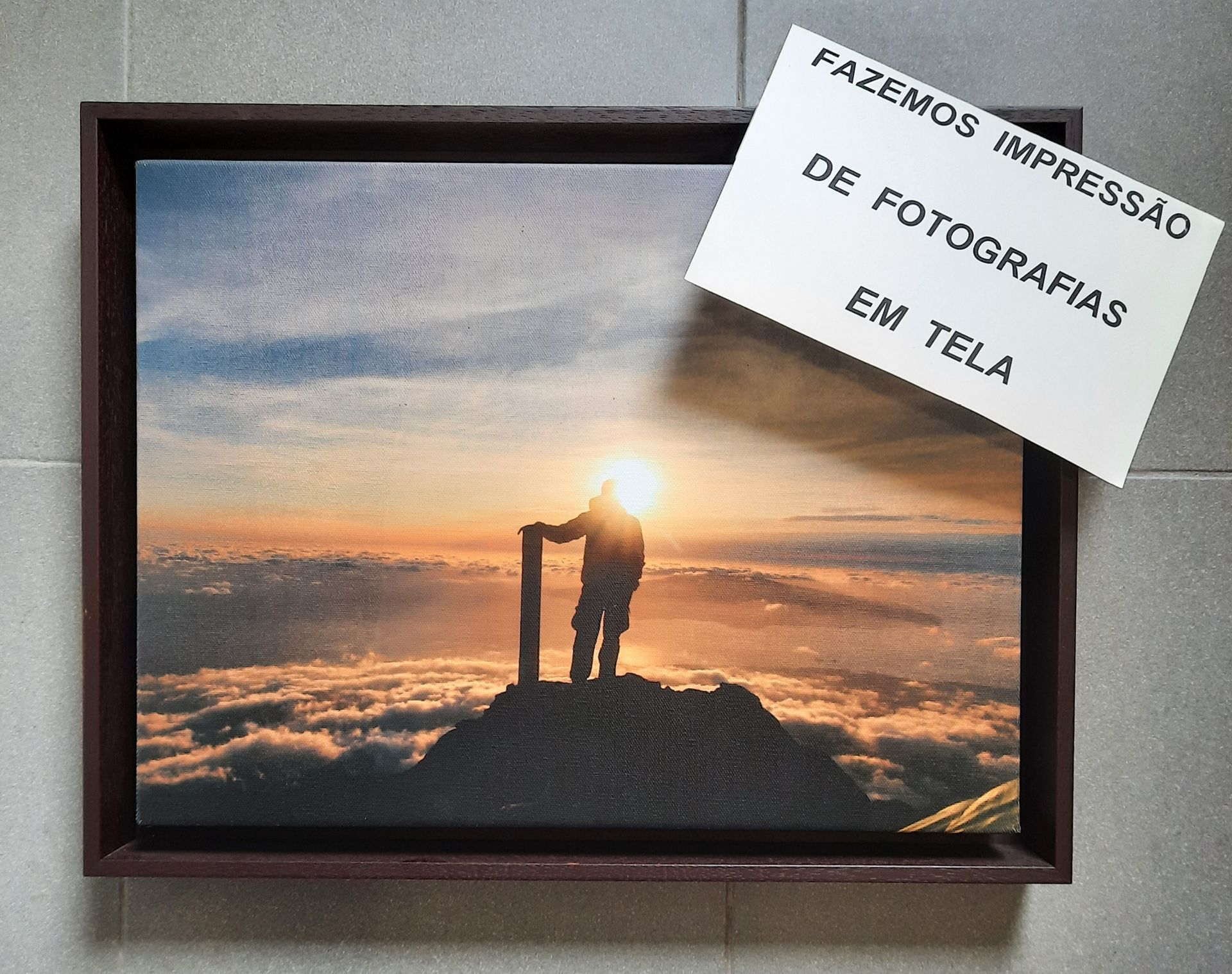Uma foto emoldurada de um homem em pé no topo de uma montanha