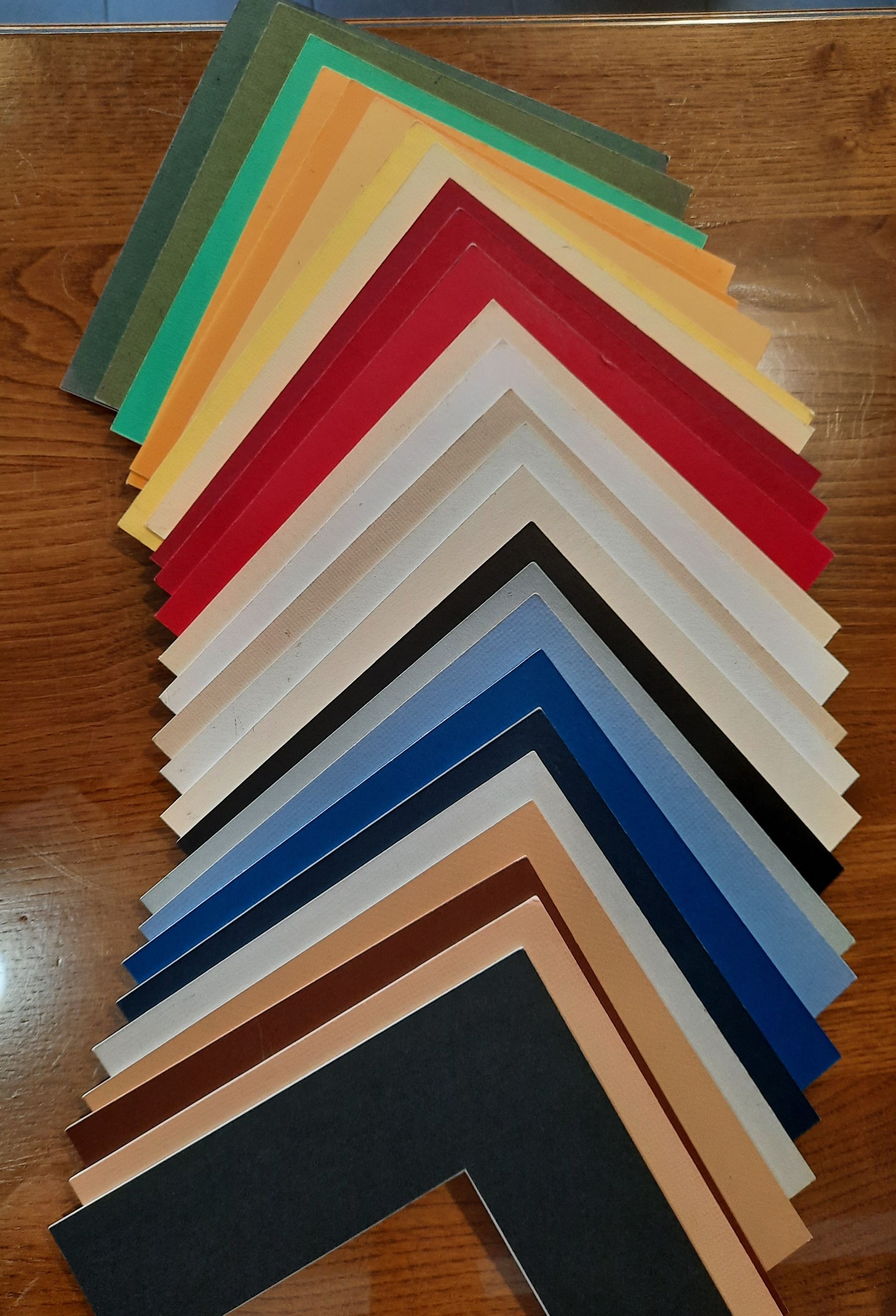 Um monte de folhas de papel de cores diferentes empilhadas umas sobre as outras sobre uma mesa de madeira.