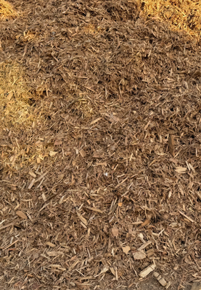 Tas de copeaux de bois bruns, probablement du paillis, en extérieur.